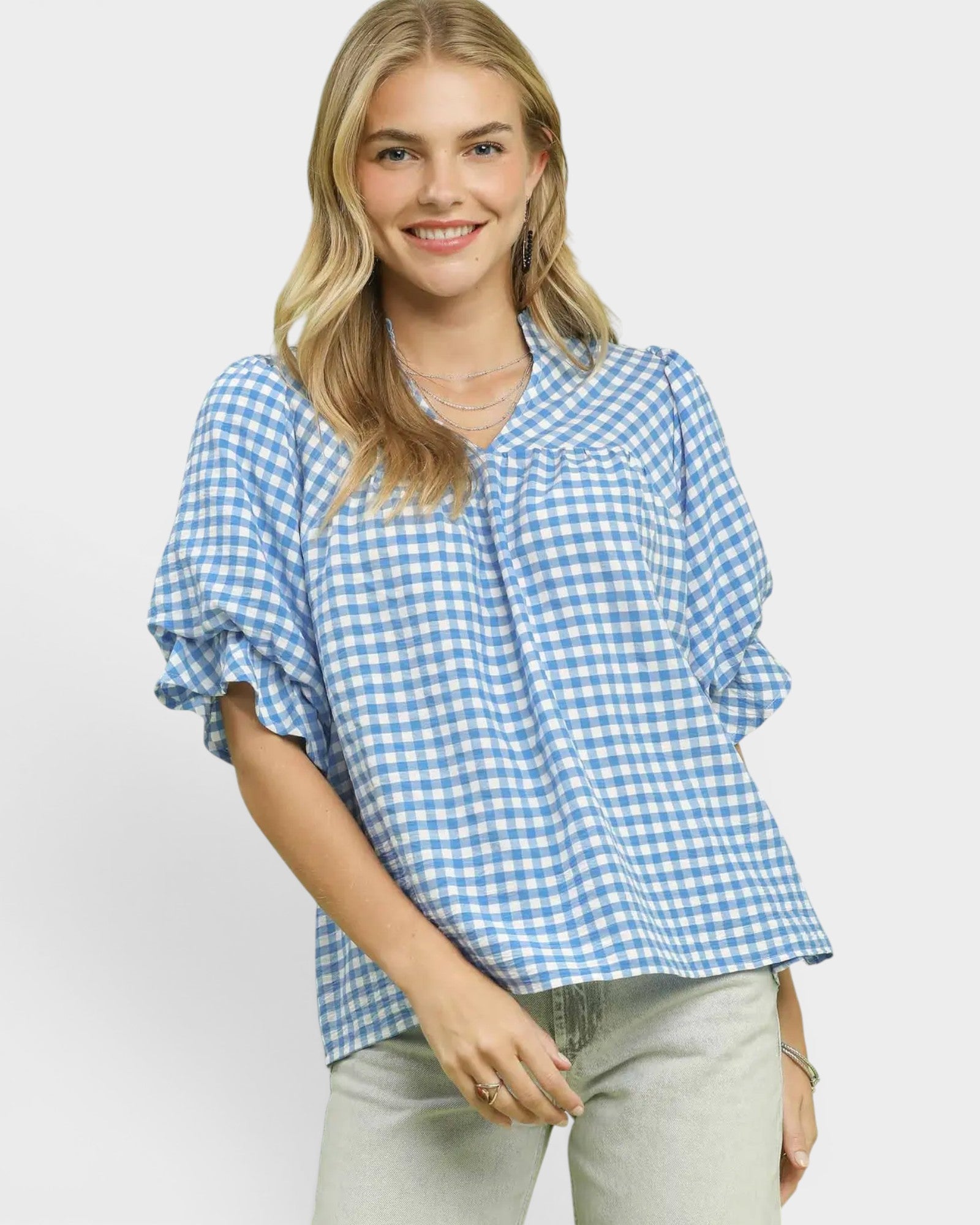 Woman wearing a blue and white checkered blouse on a light gray background