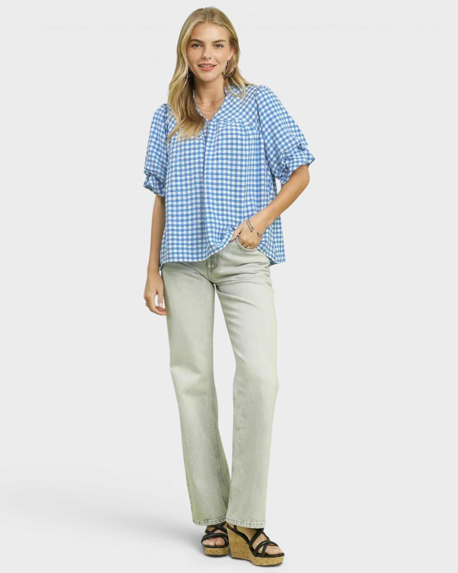 Woman wearing a blue checkered shirt and beige pants on a white background