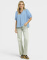 Woman wearing a blue checkered shirt and beige pants on a white background