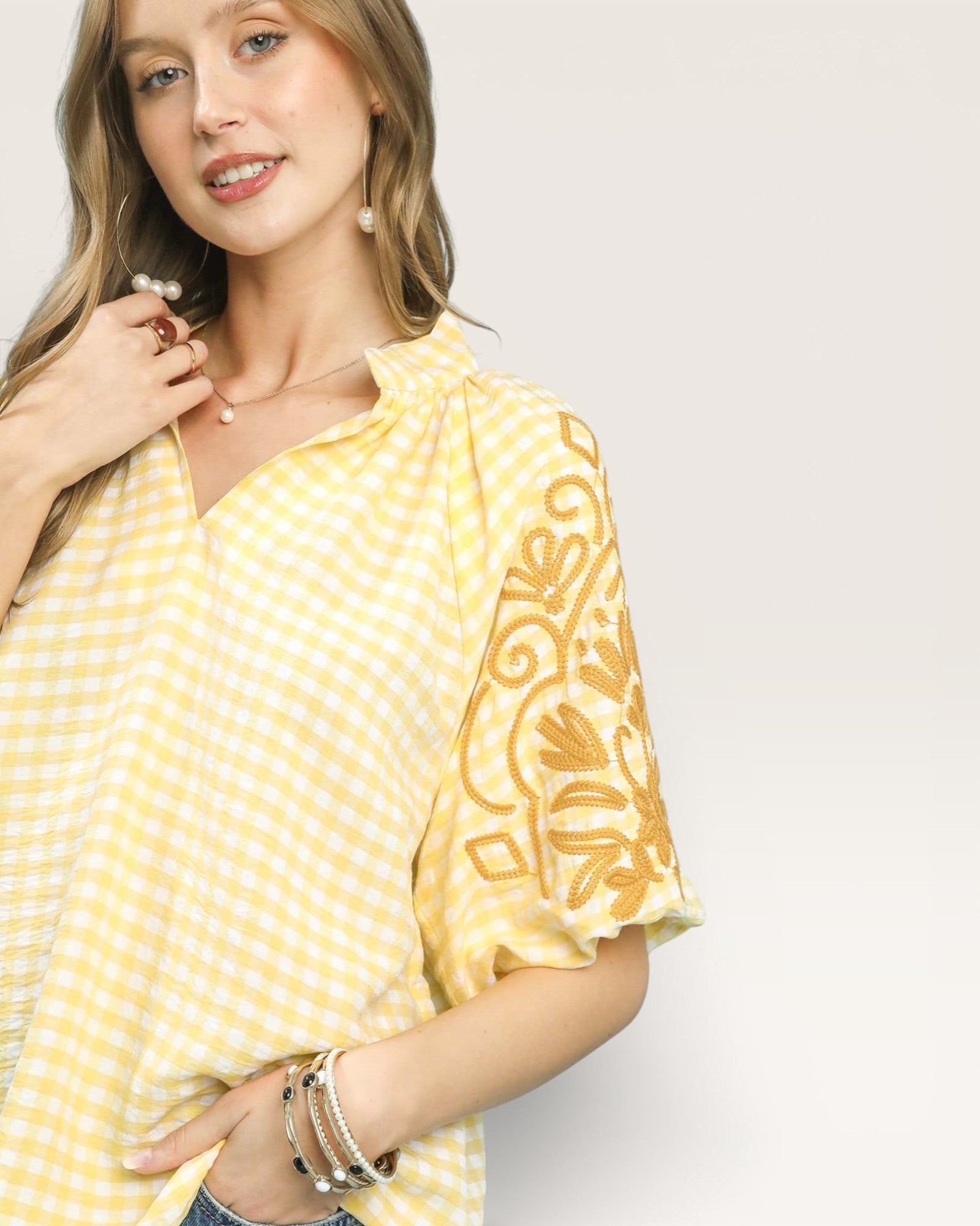 Woman wearing a yellow patterned blouse against a plain background