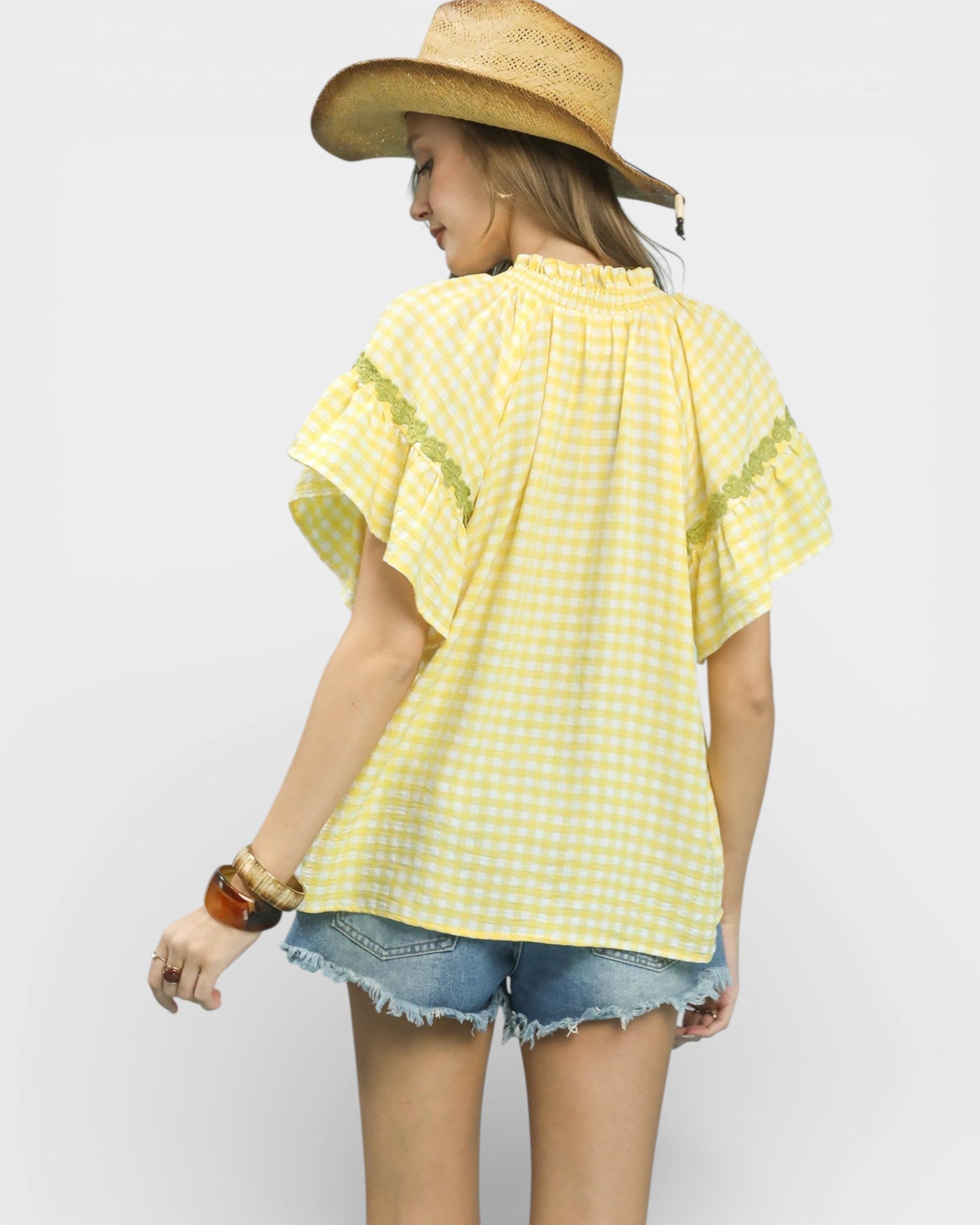 Woman wearing a yellow checkered shirt and straw hat on a white background