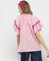 Woman wearing a pink checkered top with lace trim on a white background