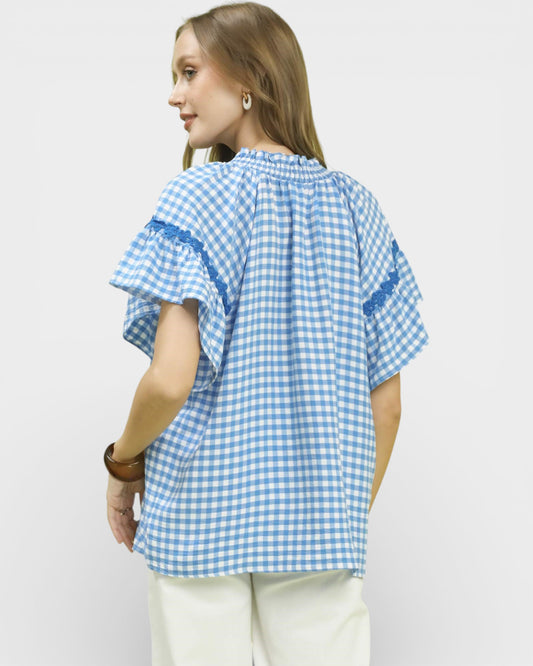 Woman wearing a blue and white checkered shirt on a light gray background