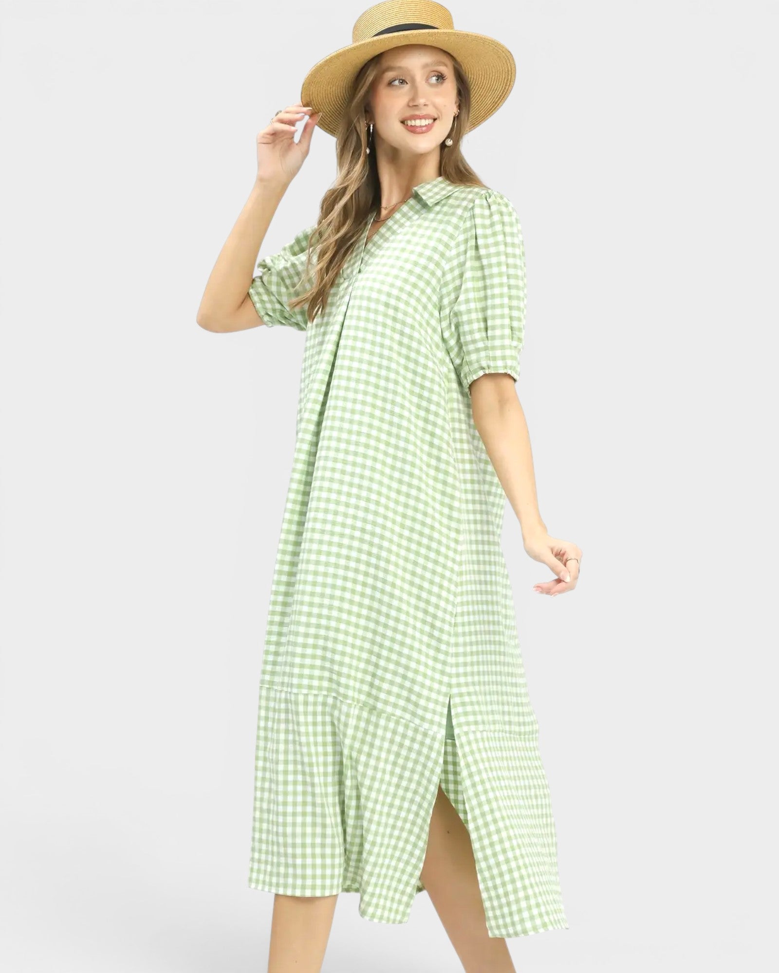 Woman wearing a green checkered dress and straw hat on a white background
