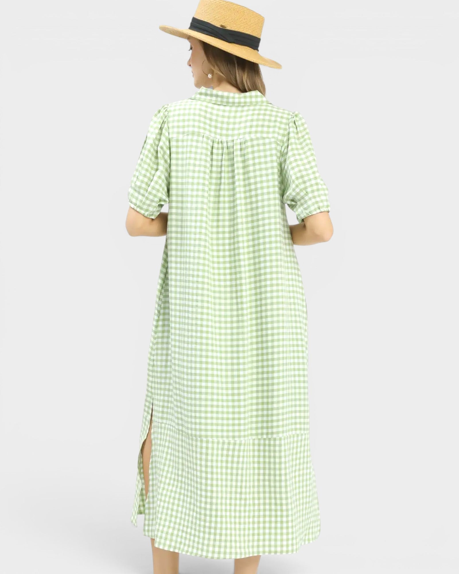 Woman wearing a green checkered dress and straw hat on a white background
