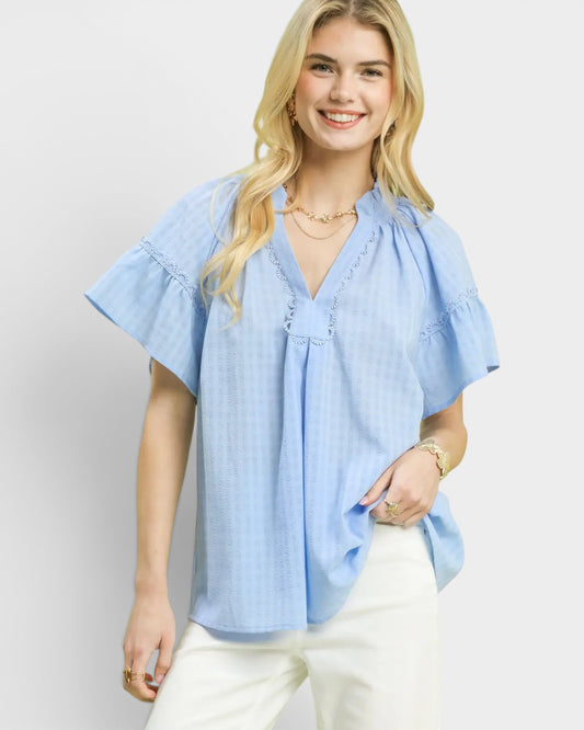 Woman wearing a light blue blouse with a plain background