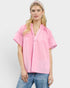 Woman wearing a pink blouse with ruffled sleeves on a white background