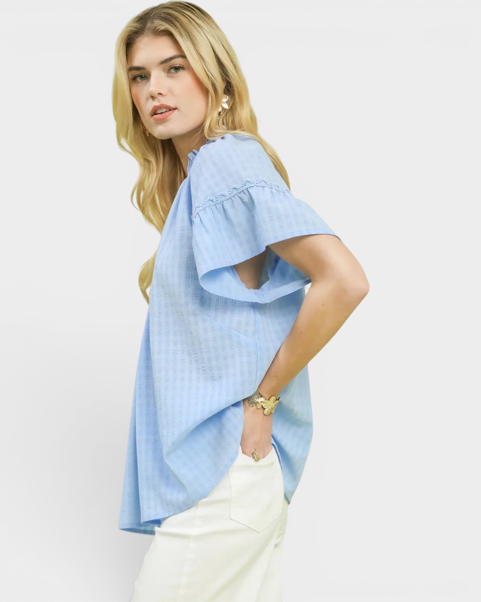 Woman wearing a light blue blouse with ruffled sleeves on a white background