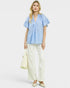 Woman wearing a light blue blouse and white pants on a white background