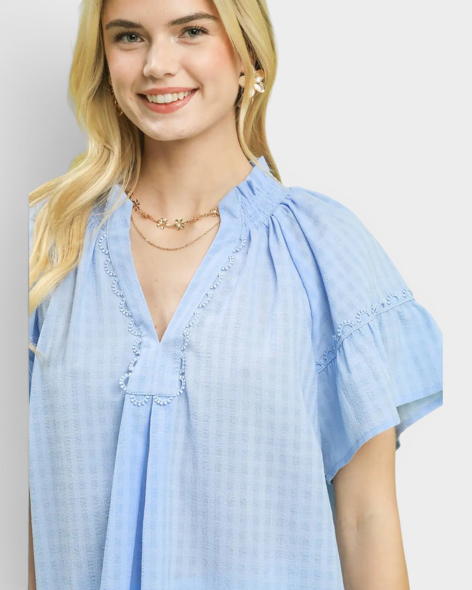 Woman wearing a light blue blouse with a plain background