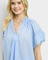 Woman wearing a light blue blouse with a plain background