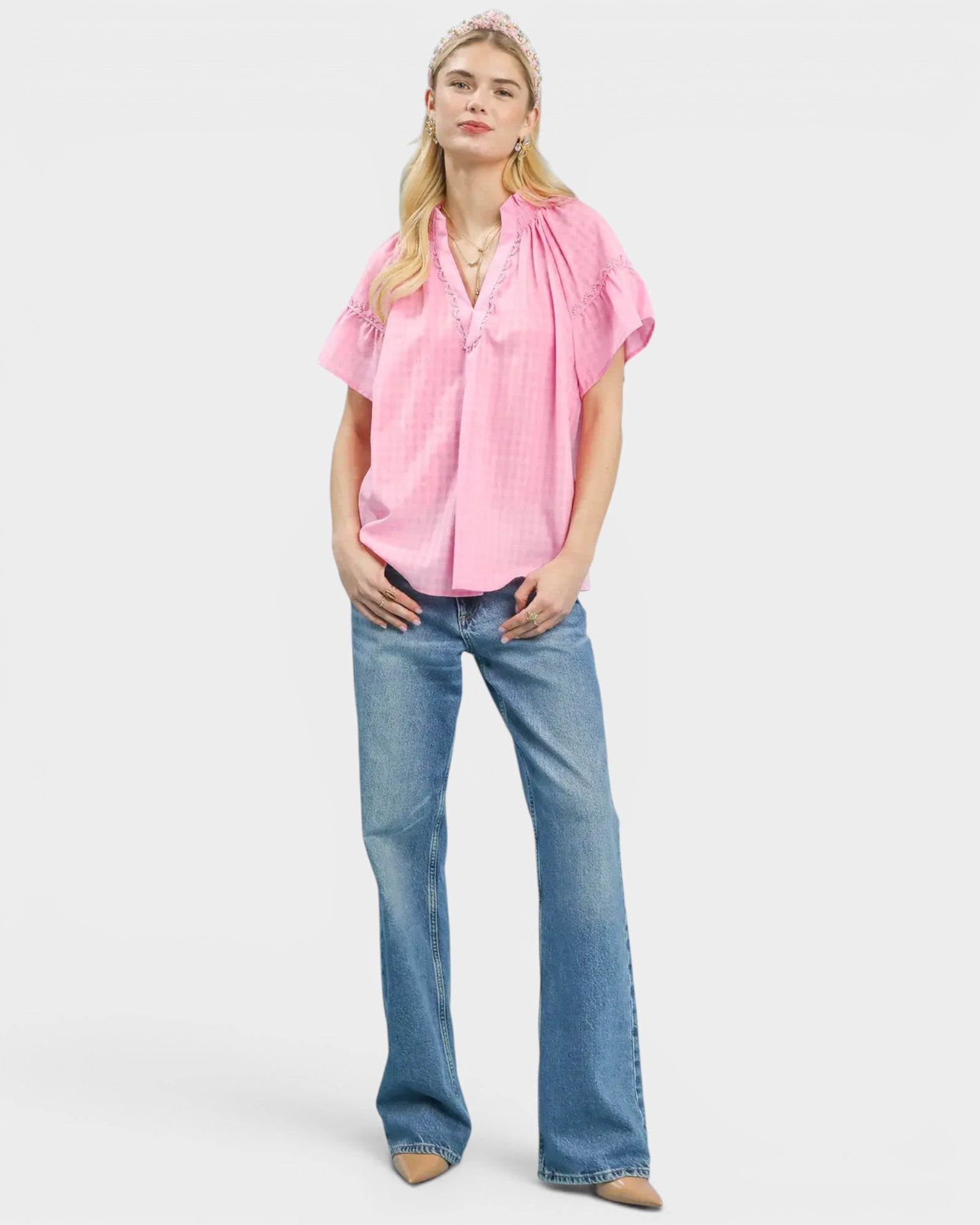 Woman wearing a pink blouse and blue jeans on a white background