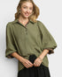 Woman wearing an olive green shirt with a plain background