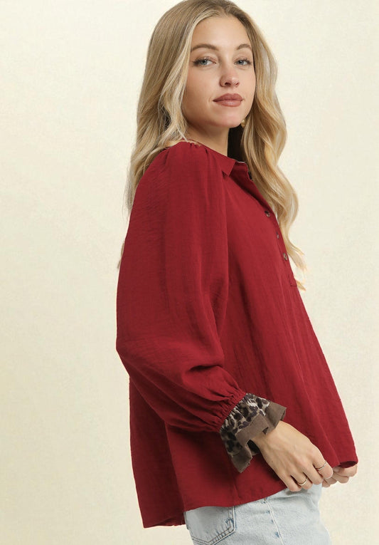 Woman wearing a red blouse with long sleeves on a beige background