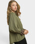 Woman wearing an olive green blouse with leopard print cuffs on a white background
