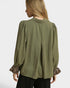 Woman wearing an olive green blouse with long sleeves and leopard print cuffs on a white background