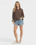 Woman wearing a brown blouse and denim shorts on a white background
