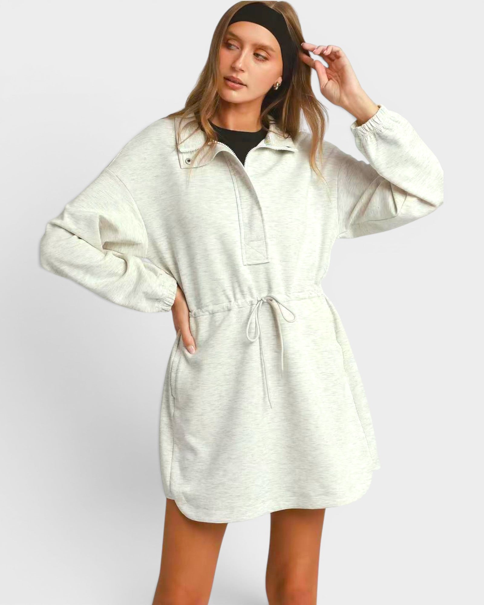 Woman wearing a light gray hoodie dress against a white background
