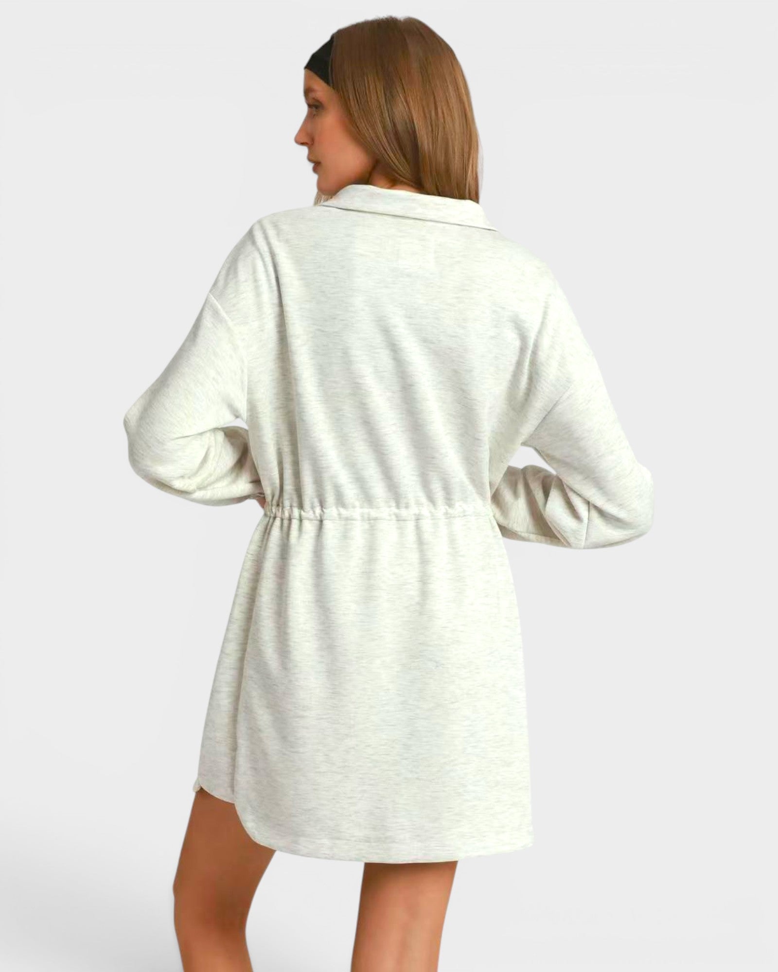 Woman wearing a white dress with long sleeves on a plain background
