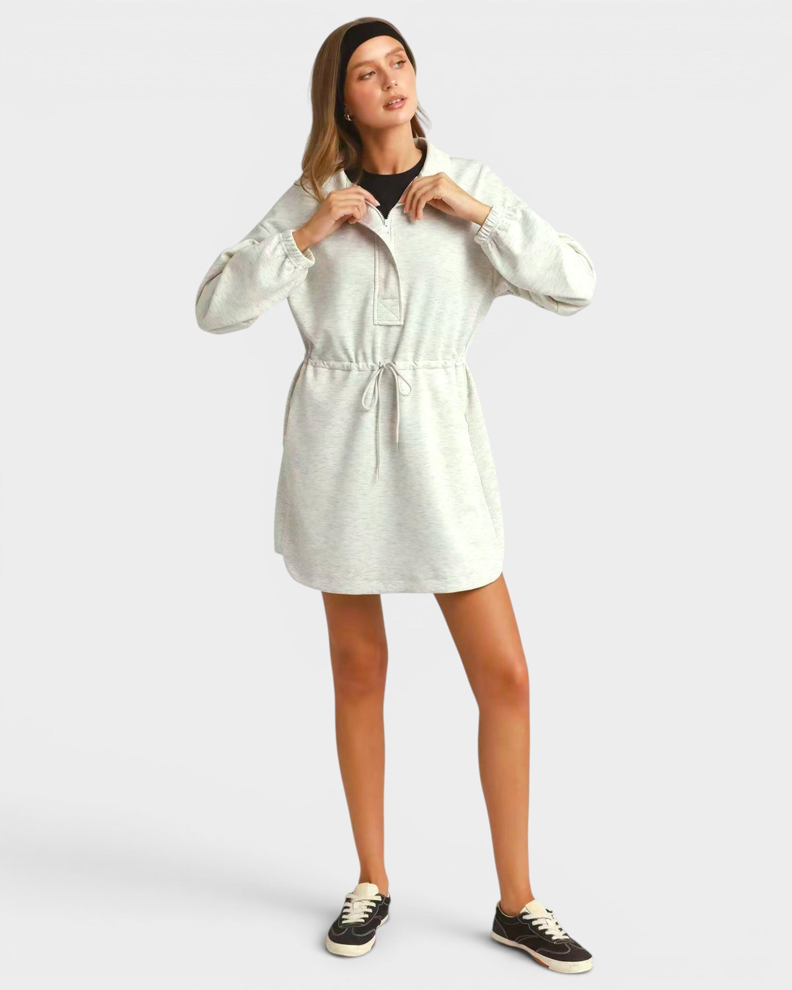 Woman wearing a light-colored dress with long sleeves on a white background