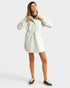 Woman wearing a light-colored dress with long sleeves on a white background