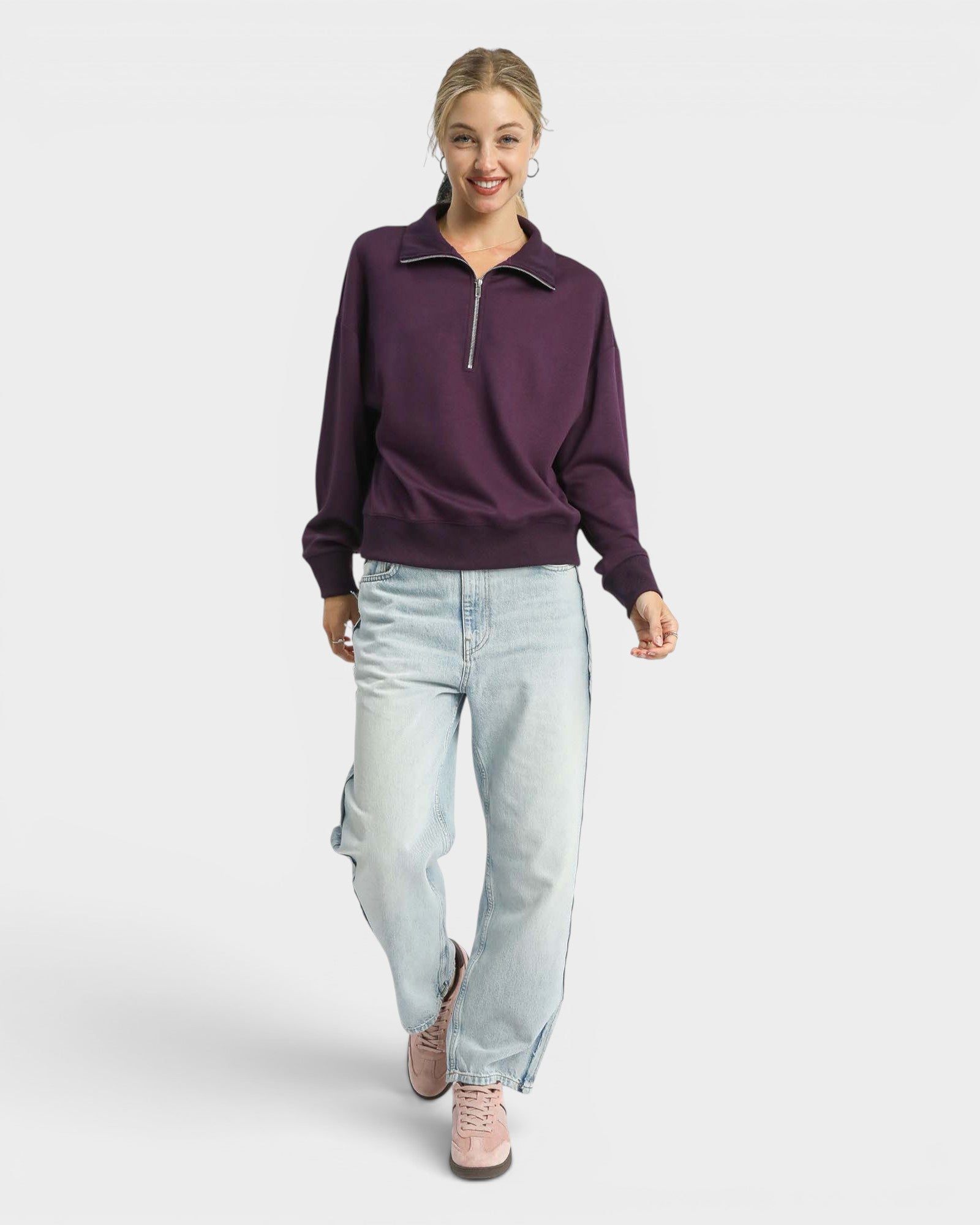 Woman wearing a purple sweater and light blue jeans on a white background