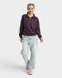 Woman wearing a purple sweater and light blue jeans on a white background