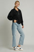 Person wearing a black sweater and light blue jeans on a plain background