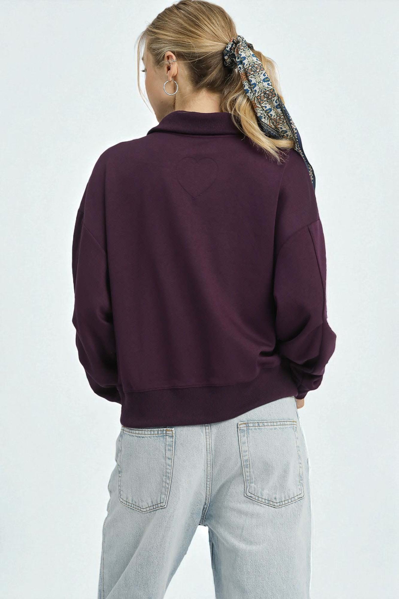 Person wearing a purple sweater and light gray pants on a white background