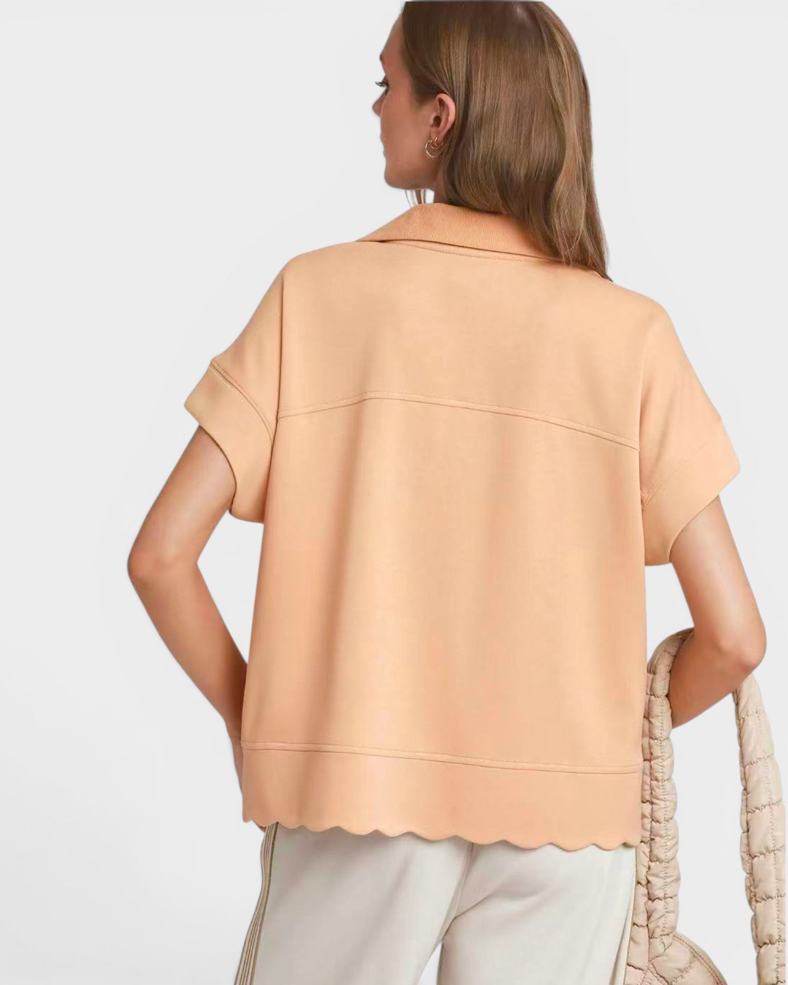 Woman wearing a beige top with a plain background