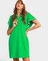 Woman wearing a green dress with white trim on a plain background