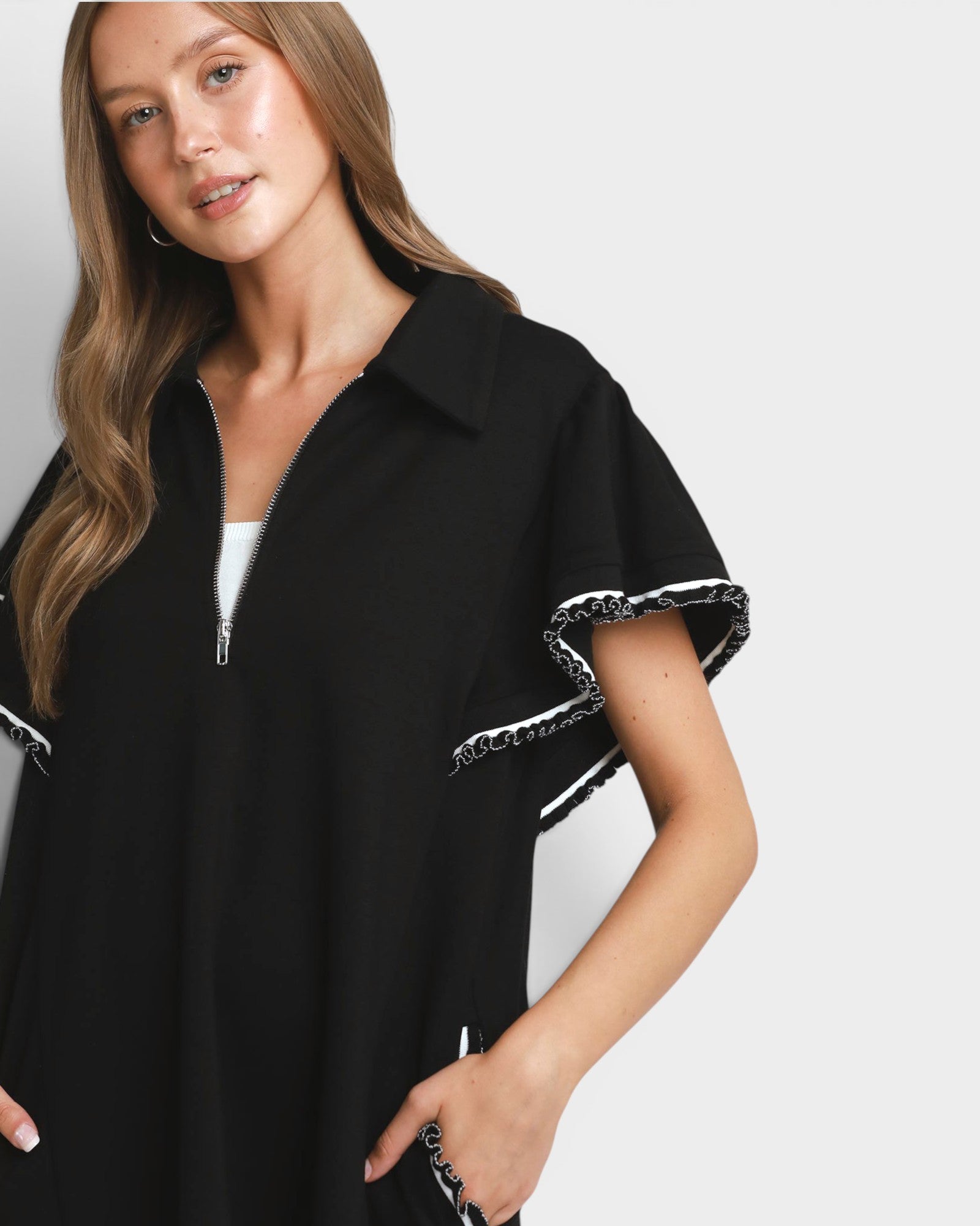 Woman wearing a black shirt with white trim on a plain background