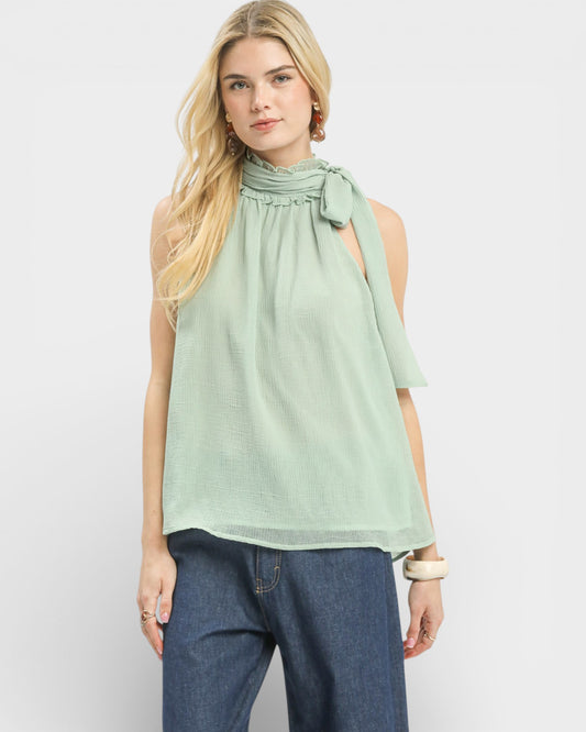 Woman wearing a light green sleeveless top with a bow detail on a white background