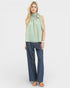 Woman wearing a light green top and blue jeans on a white background