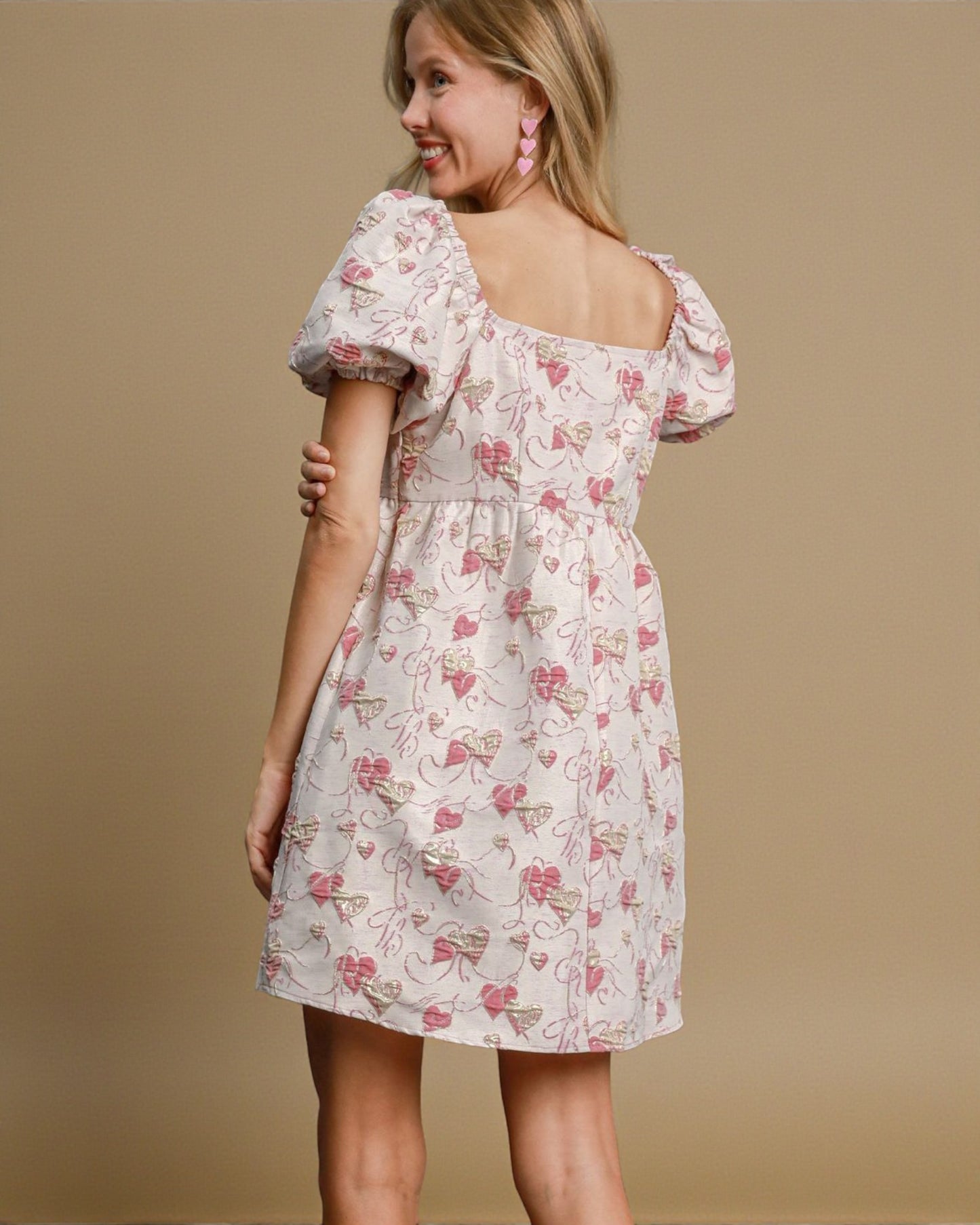 Woman wearing a floral dress with puff sleeves on a beige background