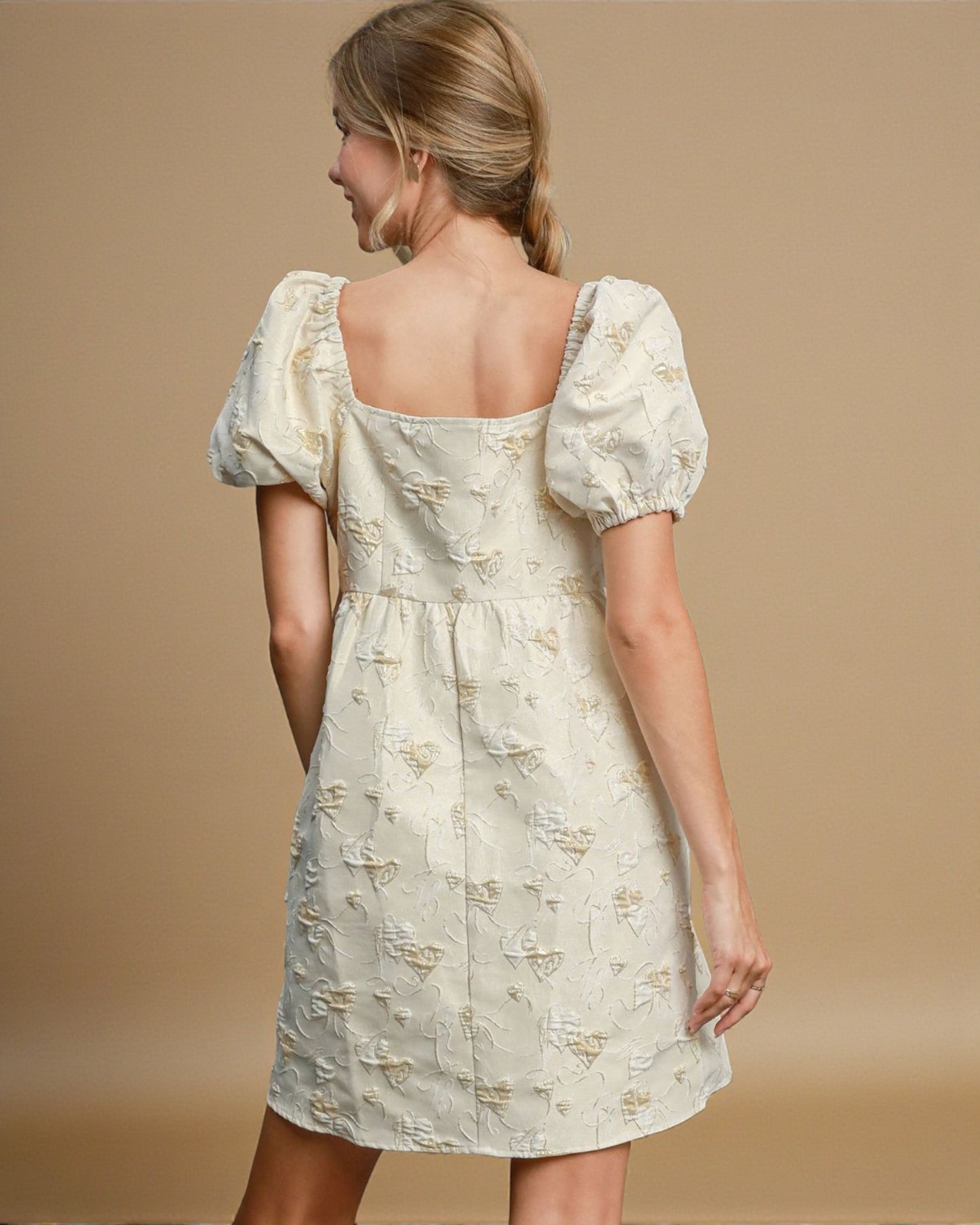 Woman wearing a light-colored dress with puff sleeves on a beige background