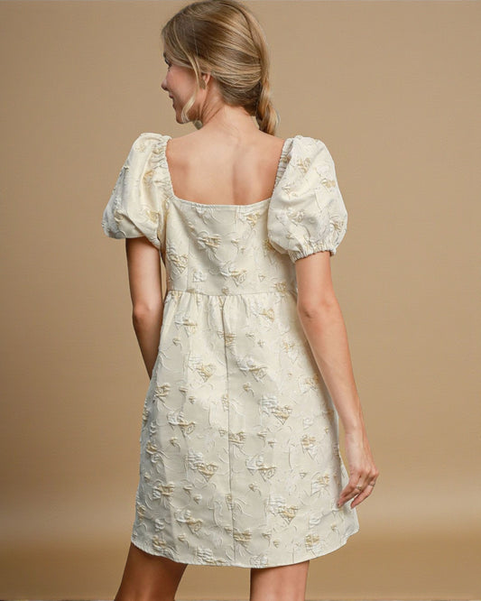 Woman wearing a light-colored dress with puff sleeves on a beige background