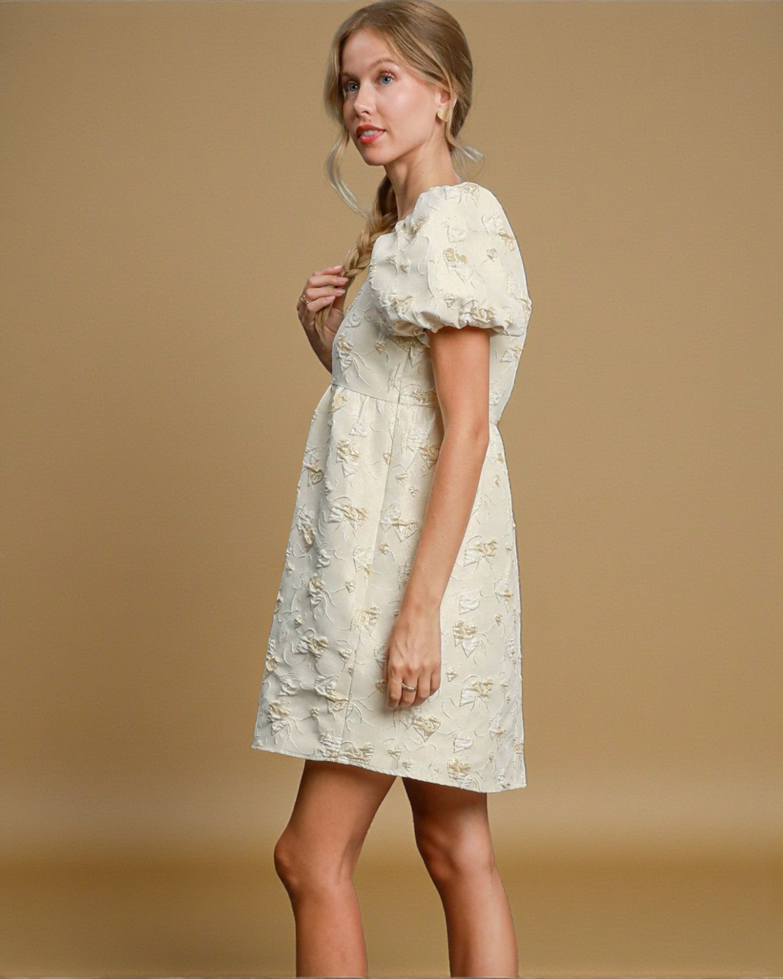 Woman wearing a white floral dress against a beige background