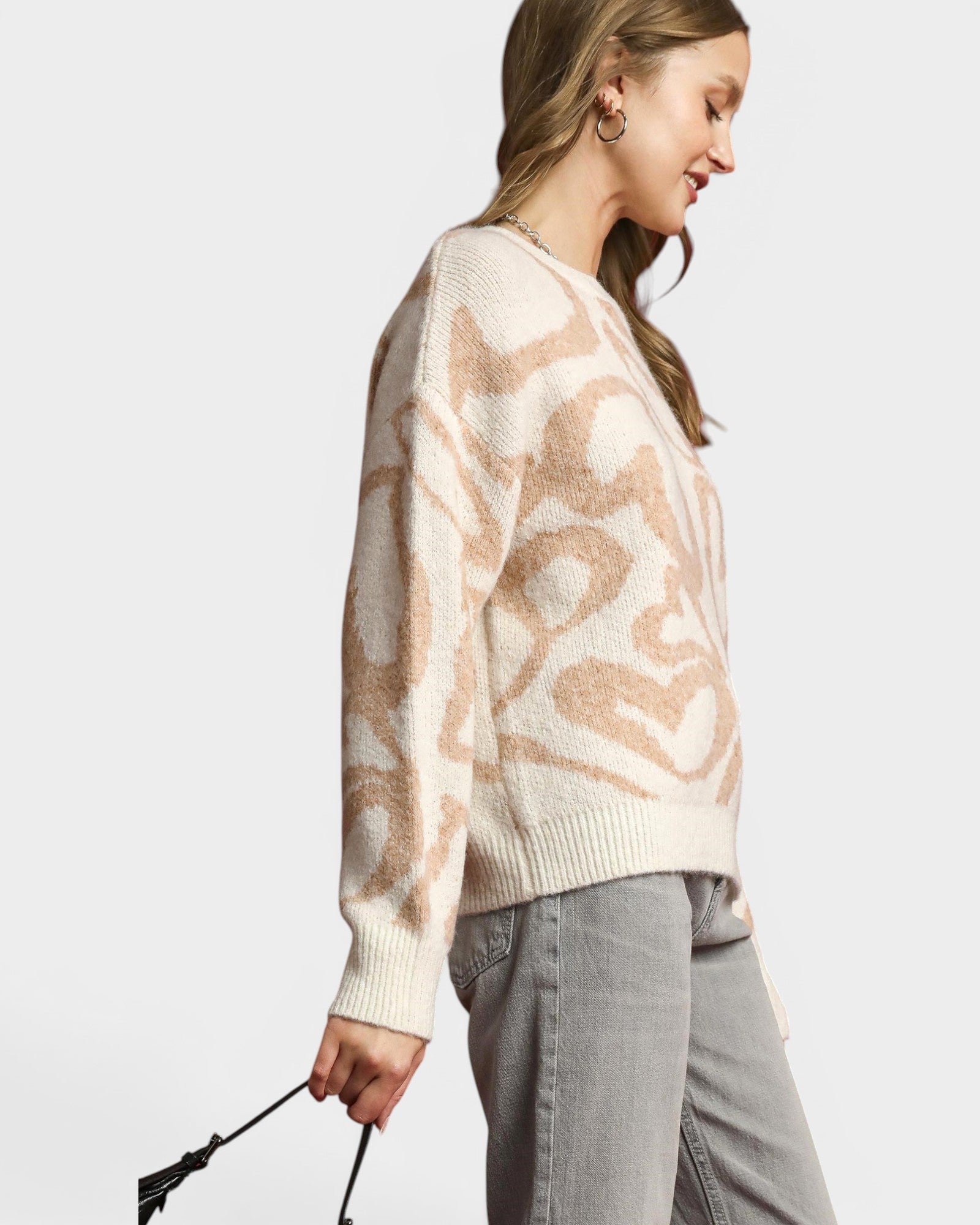 Woman wearing a patterned sweater and gray pants on a white background