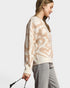 Woman wearing a patterned sweater and gray pants on a white background