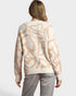 Person wearing a beige sweater with abstract pattern on a plain background
