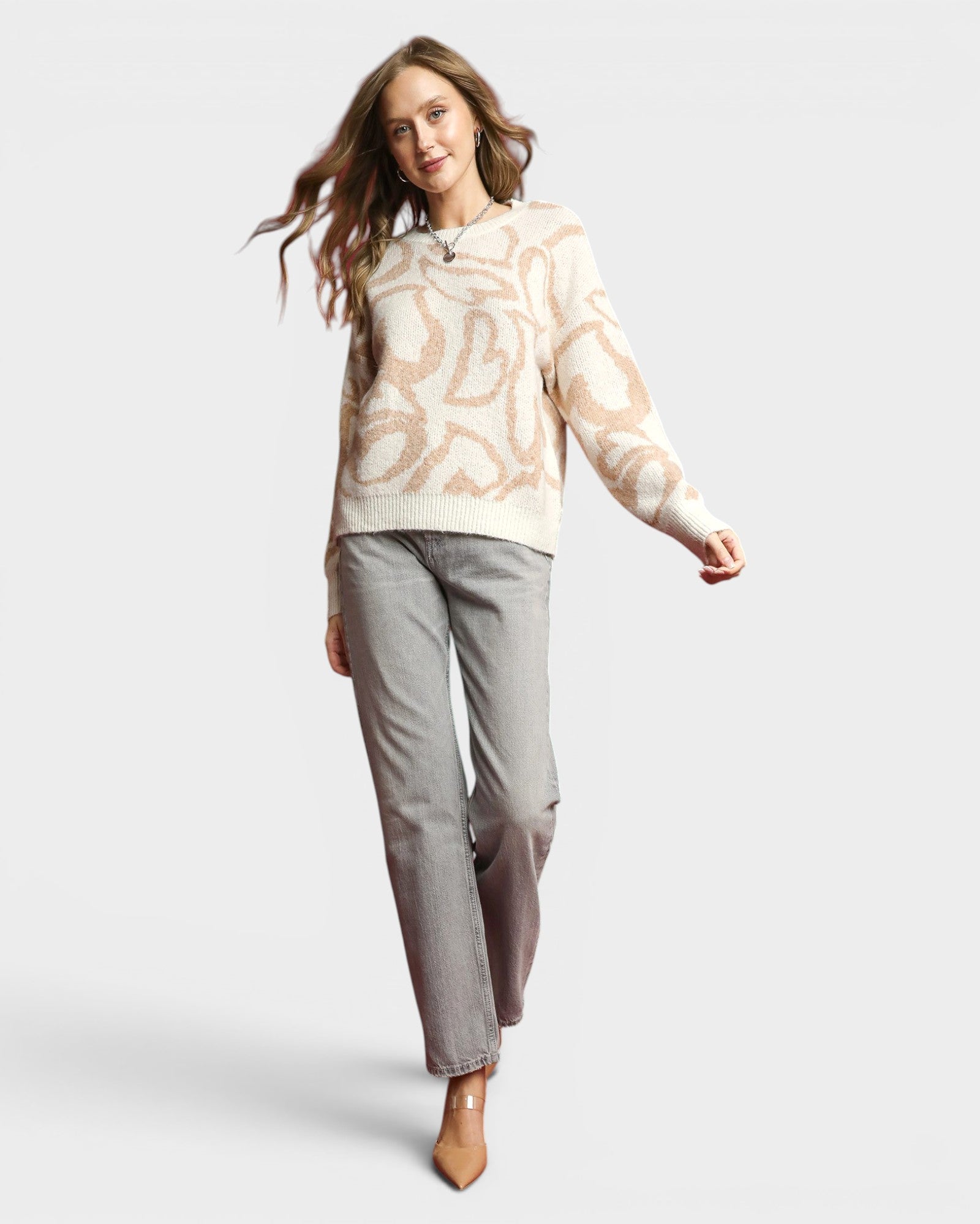 Woman wearing a patterned sweater and gray pants on a white background