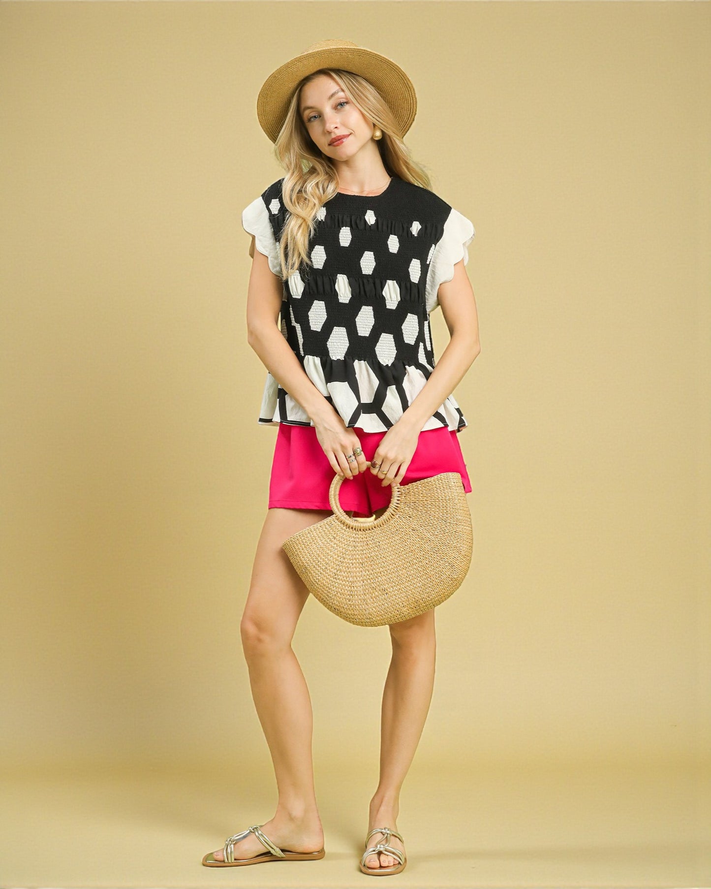 Woman holding a straw bag against a beige background