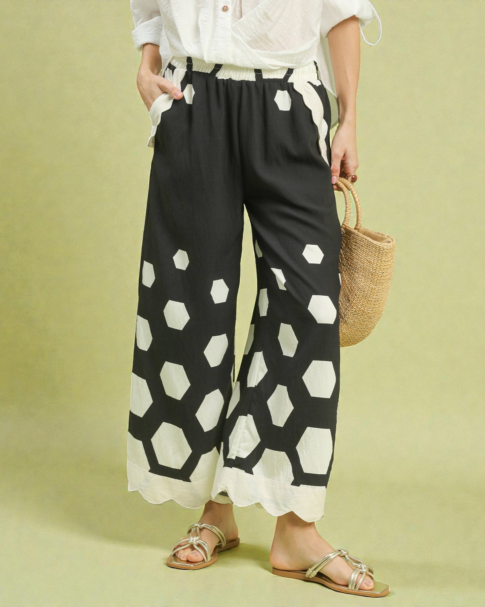 Person wearing black pants with white geometric pattern on a light green background