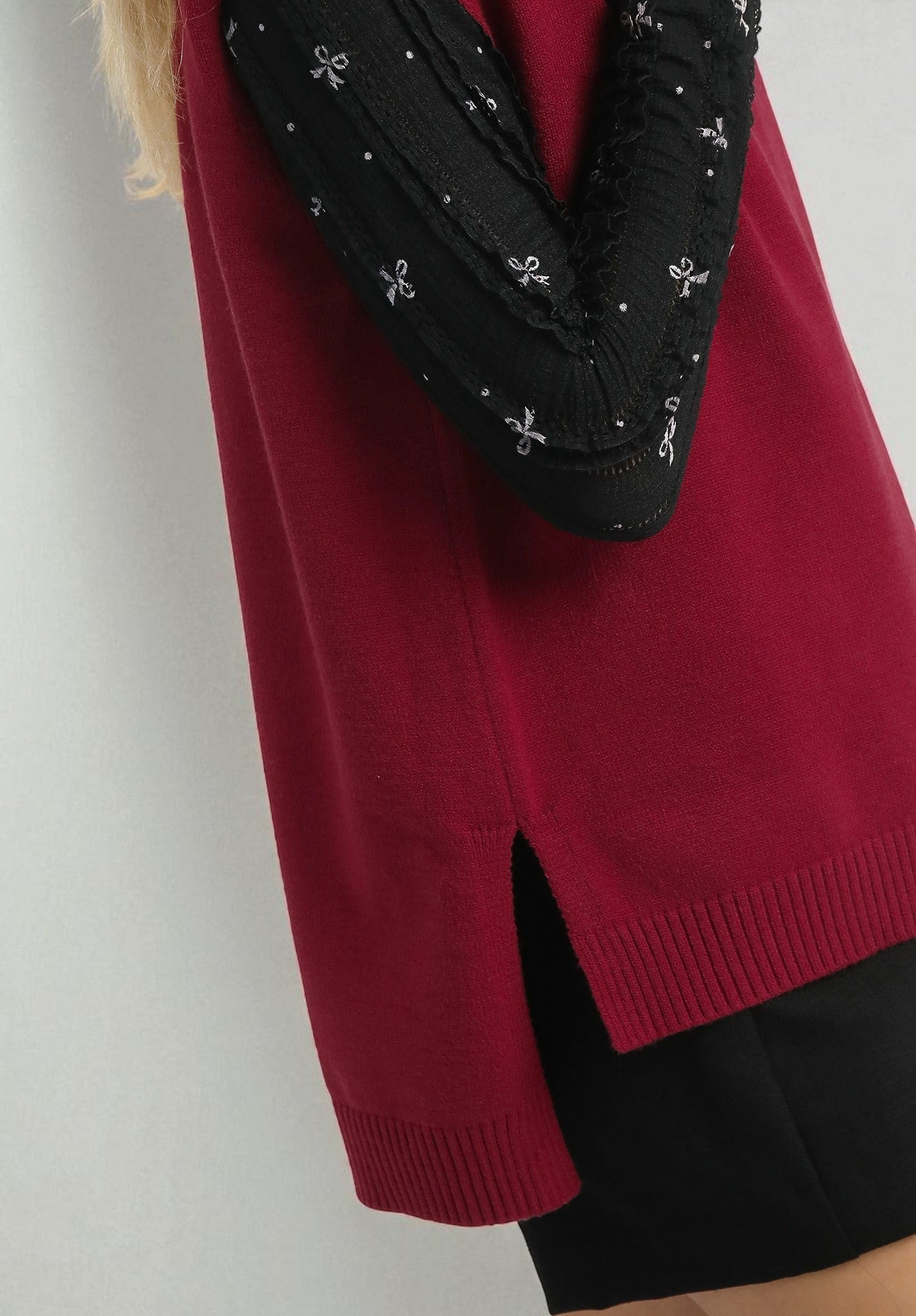 Red sweater with a black and white patterned scarf on a plain background