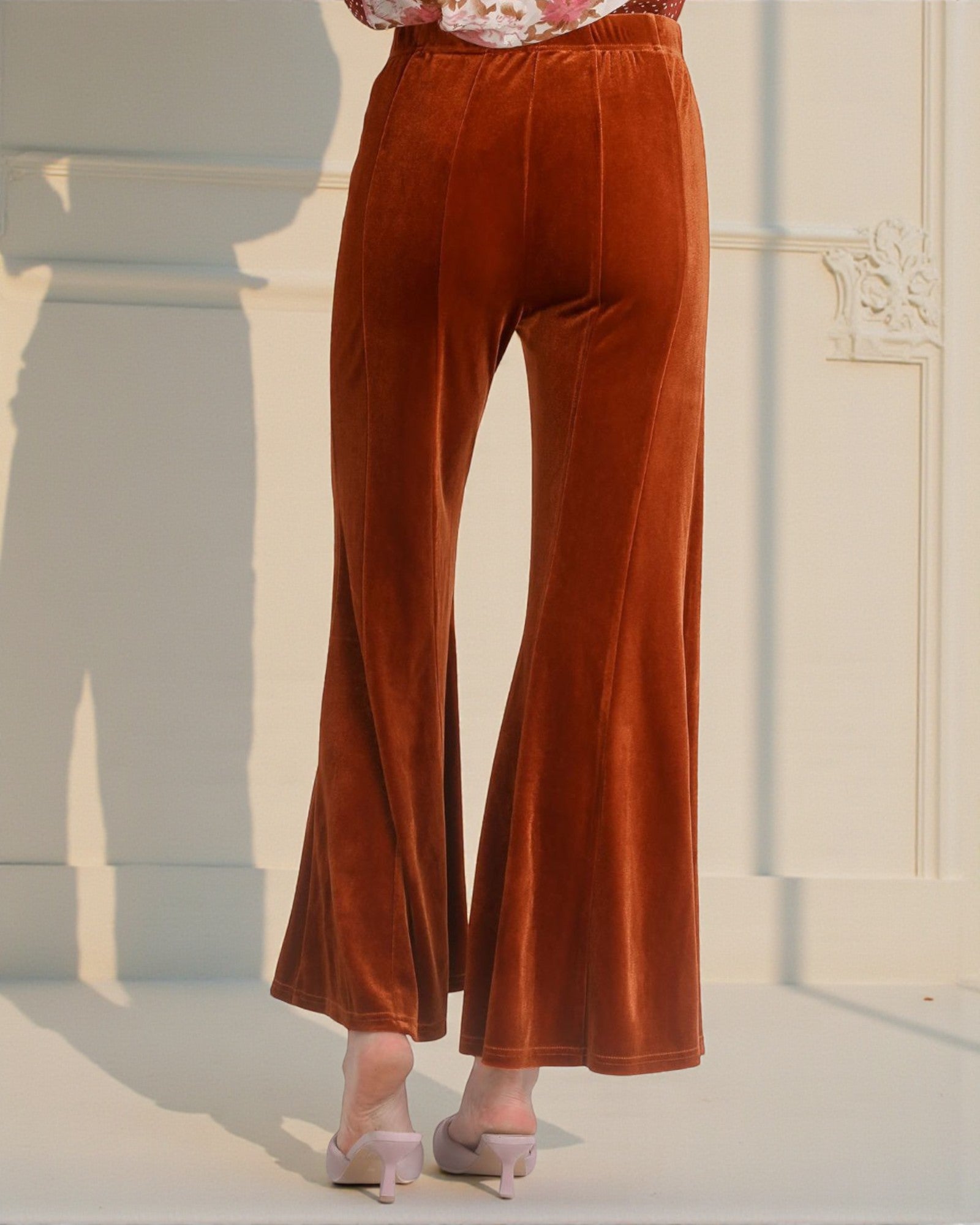 Brown velvet pants worn by a person in a softly lit room.