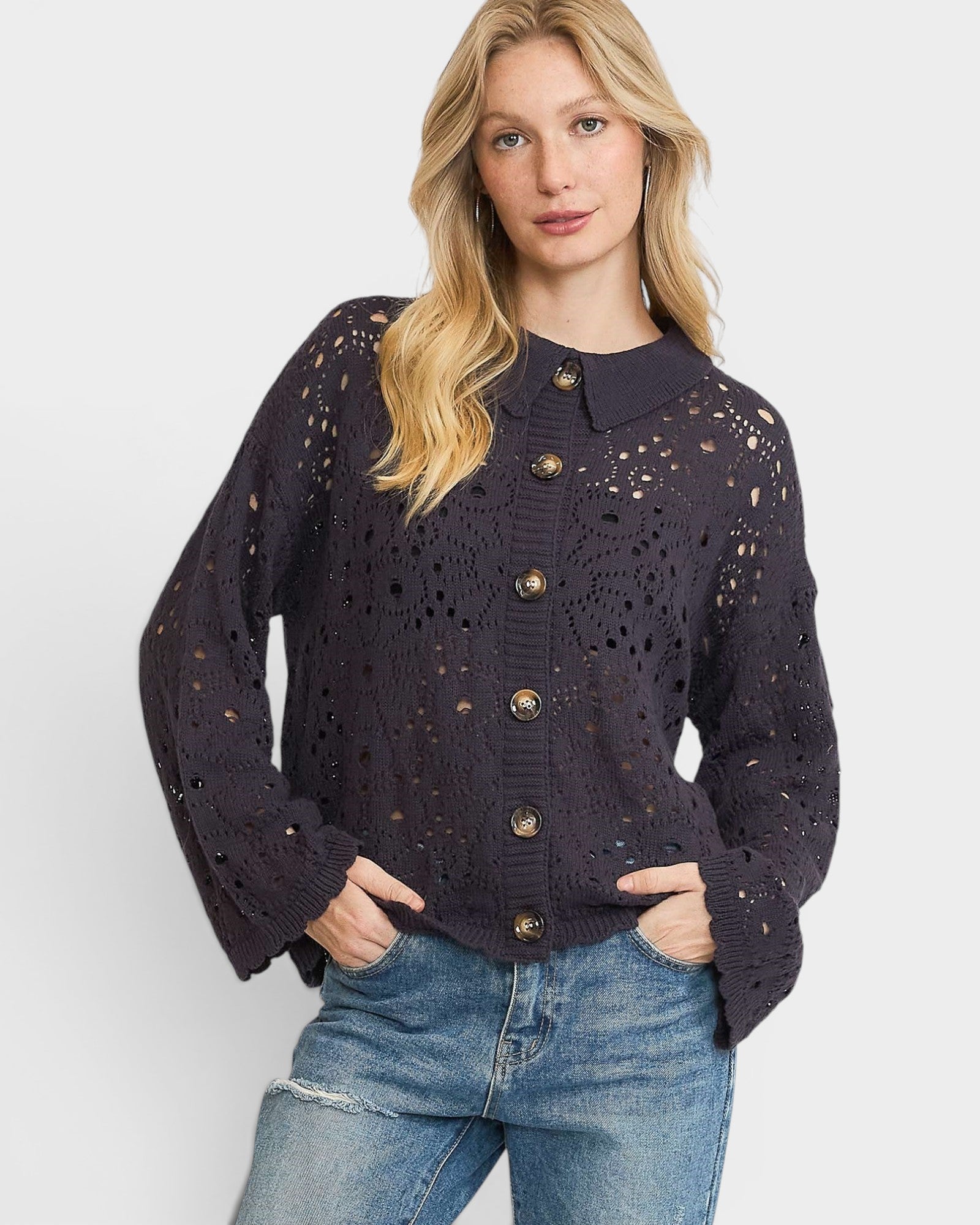 Woman wearing a dark navy open-knit cardigan with gold buttons on a white background