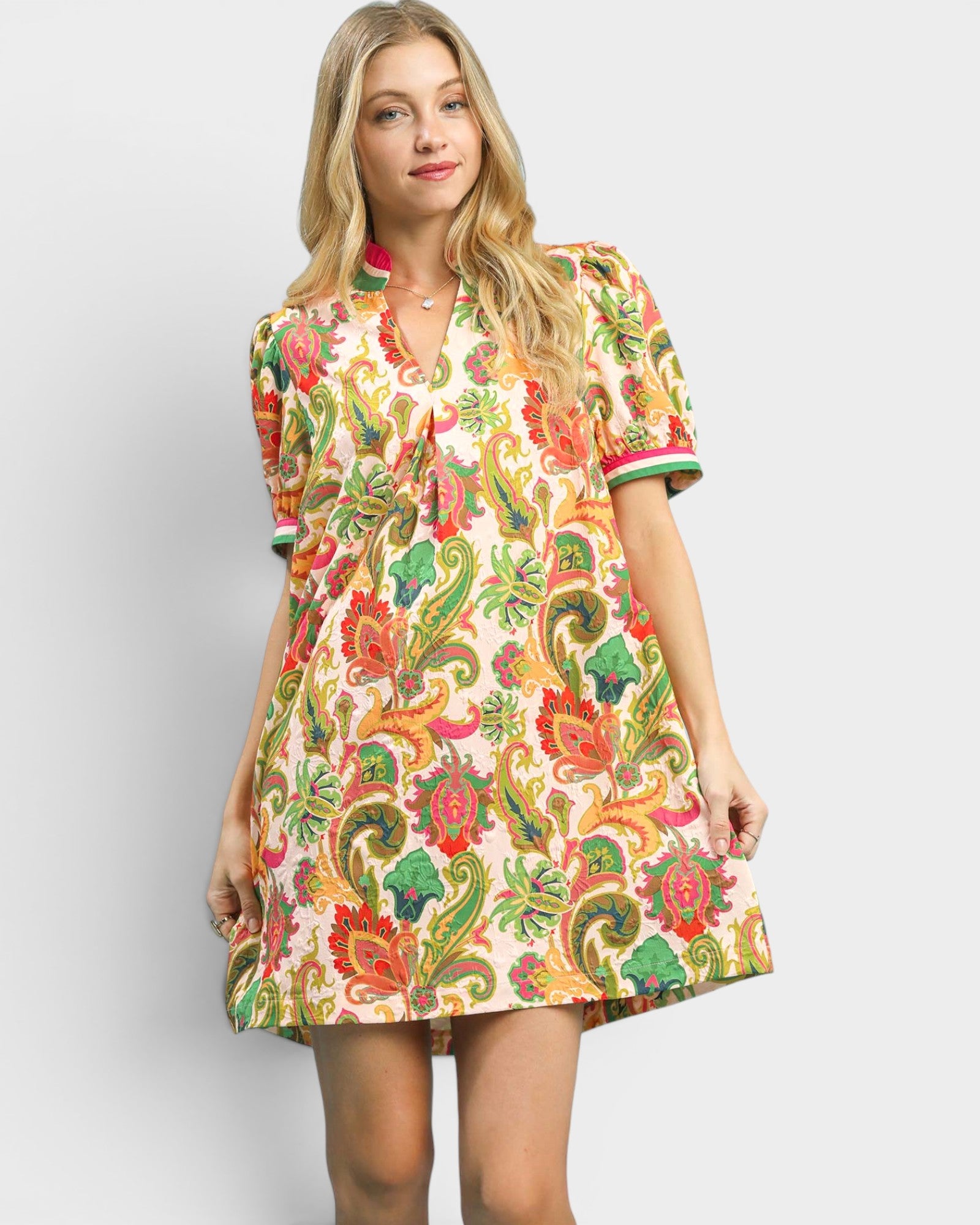 Woman wearing a colorful patterned dress on a plain background