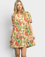 Woman wearing a colorful patterned dress on a plain background
