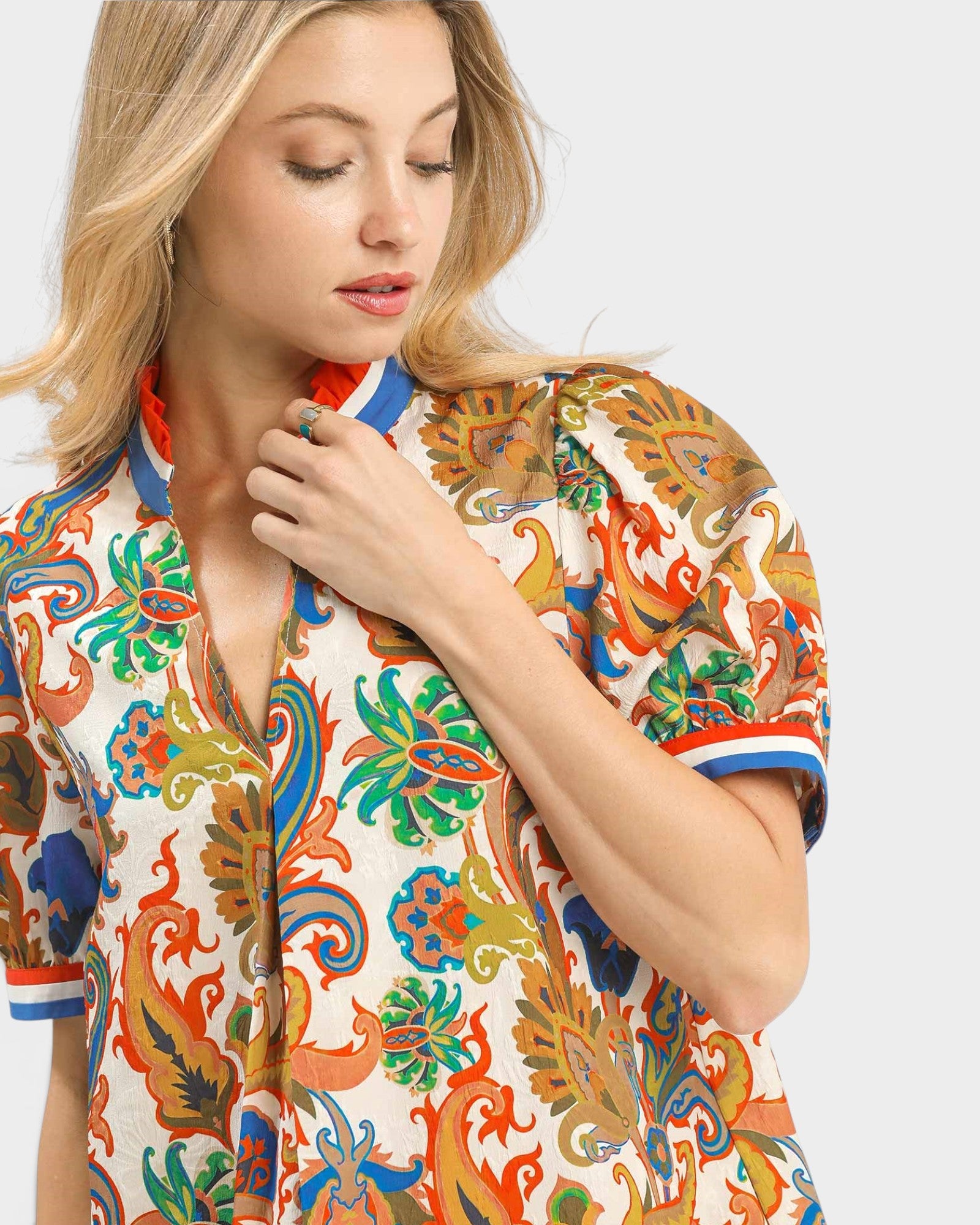Woman wearing a colorful patterned shirt on a light gray background